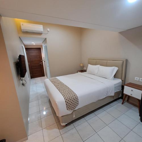 a bedroom with a white bed and a television at Christine Hotel Jogja in Yogyakarta
