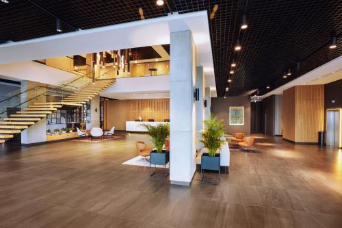 a lobby of a building with chairs and tables at Q Hotel Plus Wrocław Bielany in Wrocław