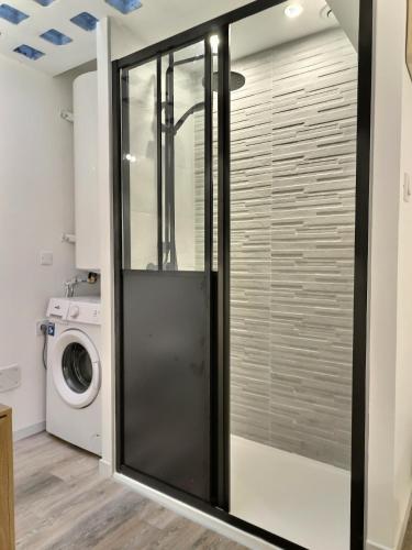 - une porte de douche en verre dans une buanderie avec un lave-linge dans l'établissement Le Petit Evali - WIFI - Centre, à Albi