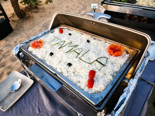a pan filled with rice and tomatoes on a table at Tamala Beach Resort in Kotu