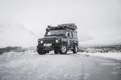 um jipe a conduzir por uma estrada coberta de neve em Land Rover Defender Luxury Camper em Morpeth