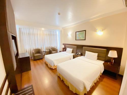 a hotel room with two beds and a chair at Muong Thanh Thanh Nien Vinh in Vinh