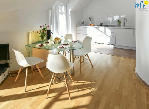 Un comedor con una mesa de cristal y sillas blancas. en Villa Nautilus Wohnung Marilena, en Wangerooge