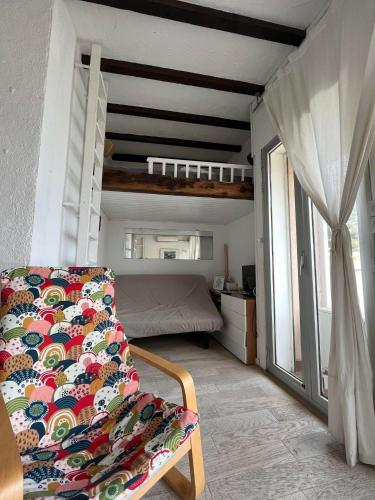 Cette chambre comprend une chaise, un lit et une fenêtre. dans l'établissement 4DEMO2 Appartement vue mer, à Collioure
