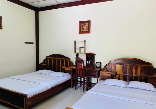 a bedroom with two beds and a desk and a table at Khách sạn Sao Mai in Ben Tre