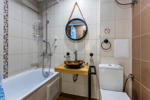een badkamer met een bad, een toilet en een spiegel bij Touristic Complex Hacienda Beach Apartments Sozopol in Sozopol