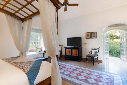 a bedroom with a canopy bed and a television at The Oberoi Rajvilas Jaipur in Jaipur