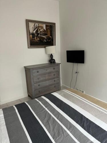 a bedroom with a bed and a dresser and a tv at Logement plein centre royan in Royan