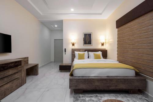a bedroom with a bed and a flat screen tv at BKT Cribs - Apartments & Suites in Abuja