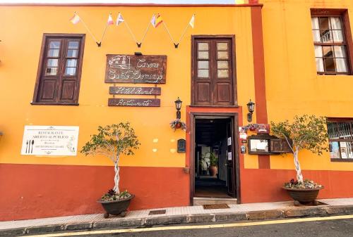 een geel en oranje gebouw met bomen ervoor bij Hotel rural casona Santo Domingo in Güimar