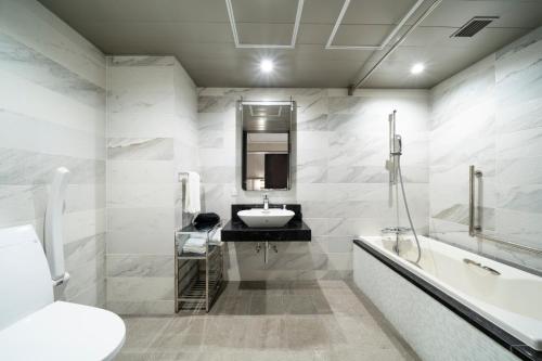 a bathroom with a sink and a mirror and a tub at KOKO HOTEL Premier Nihonbashi Hamacho in Tokyo