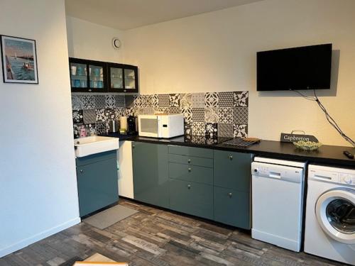 a kitchen with a washing machine and a tv on the wall at Horizon Océan 1 - Superbe appartement 2 pièces avec parking privatif in Capbreton