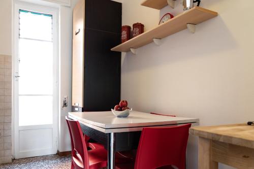 a kitchen with a white table and red chairs at Accomodo MIT12 Trivano Linate in Milan