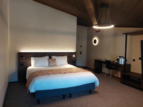 CourtedouxにあるKza Jura Swissのベッドとデスクが備わるホテルルームです。