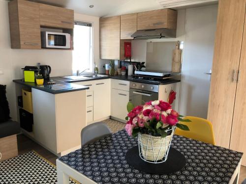 uma cozinha com uma mesa com um vaso de flores em CANET Plage Mobil Home Nicky em Canet-en-Roussillon
