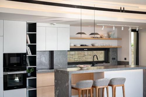a kitchen with white cabinets and bar stools at Vicky's Island View in Marathi
