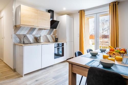 une cuisine avec des armoires blanches et une table avec des chaises dans l'établissement Une bulle de quiétude au cœur du Doubs, à Audincourt