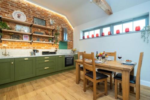 a kitchen with green cabinets and a wooden table at Alde Bay Farm - Coral Cottage in Aldeburgh