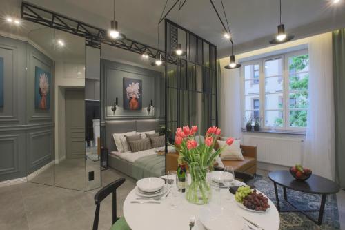 a living room with a bed and a table with flowers at Glamour Jacuzzi Apartment in Krakow