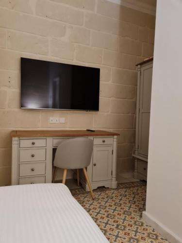 1 dormitorio con escritorio y TV en la pared en Typical Maltese Maisonette in St.Julians, en San Julián