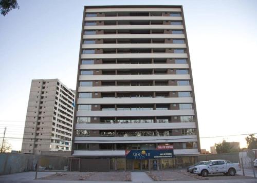 um edifício alto com um carro estacionado em frente em Departamento Estudio en Calama em Calama