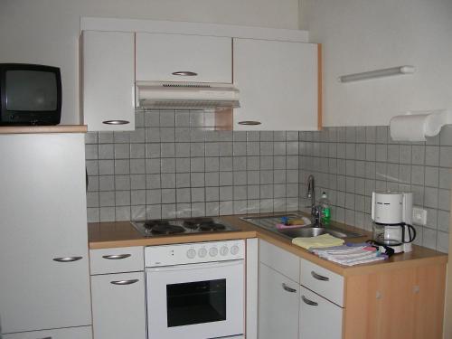 a small kitchen with white cabinets and a sink at Haus Schmidl in Zell am See