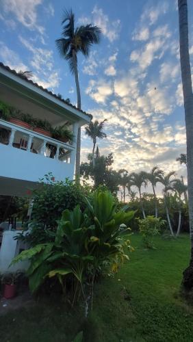 a house with palm trees in front of a yard at Charming 1 bdr apt w/ pool 5min Popi beach in Las Terrenas
