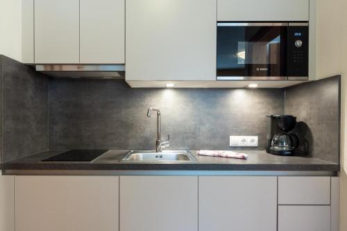 una cocina con armarios blancos y fregadero en Falkner Appartement Resort, en Längenfeld