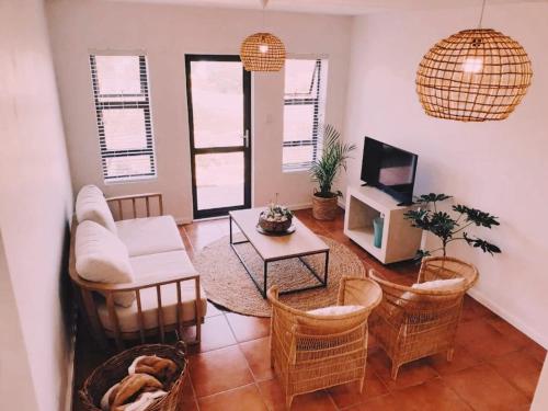 a living room with a couch and chairs and a tv at Struispaleis in Struisbaai