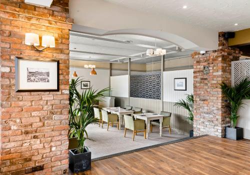 a dining room with tables and chairs and a brick wall at Dragonfly Hotel King's Lynn in Kings Lynn