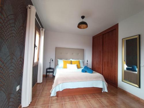 a bedroom with a bed with yellow and blue pillows at Vista Volcán in Lajares