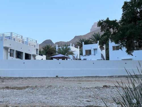 a white wall in front of some white houses at Wadi Al Arbeieen Resort in Muscat