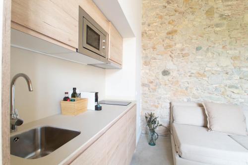 a kitchen with a sink and a stone wall at Domina Boutique Apartment in Girona