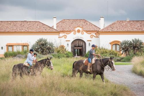 a group of people riding horses in front of a house at El Colibri - Relais & Châteaux in Santa Catalina