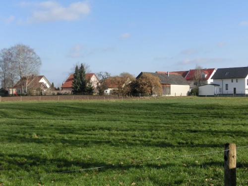 un campo de césped verde con una valla y casas en Weberhof, en Egenhofen