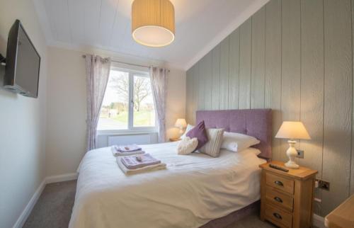 Schlafzimmer mit einem großen Bett und einem Fenster in der Unterkunft Luxury family Beechwood lodge with hot tub in Lochwinnoch