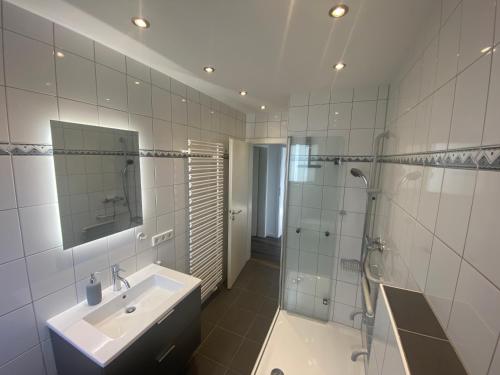 a white bathroom with a sink and a shower at Komfort-Apartment BIRKE in Tönisvorst