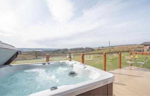 a hot tub with a view of a field at Luxury family Beechwood lodge with hot tub in Lochwinnoch