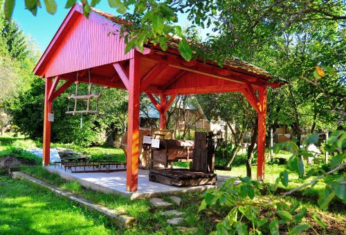 a red pavilion in a garden with a table and bench at Kis-Balatoni Ökoporta in Zalaszabar