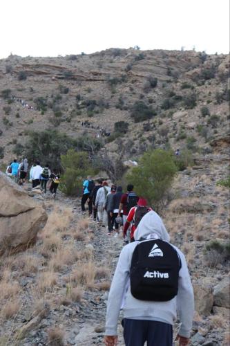a group of people walking down a rocky trail at Cloudy Cloud Farm Resort in Izkī