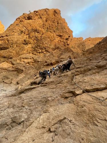 a group of people climbing up a rocky mountain at Cloudy Cloud Farm Resort in Izkī