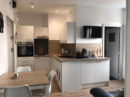 une cuisine avec des armoires blanches et une table et des chaises dans l'établissement Studio le p'tit Wims à 350 m de la plage, à Wimereux