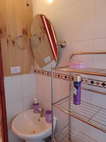a small bathroom with a sink and a mirror at Cabaña del Volcán in Licán Ray