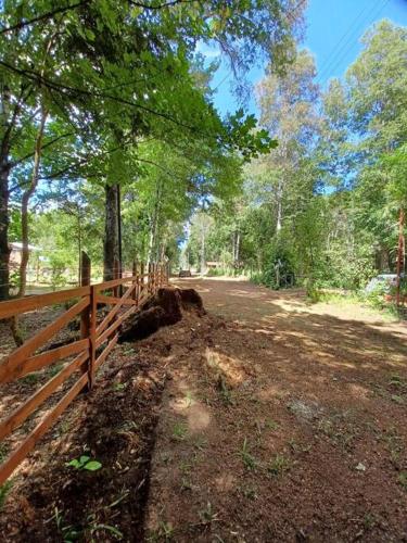 a wooden fence next to a dirt road with trees at Cabaña del Volcán in Licán Ray