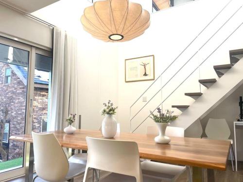 a dining room with a wooden table and white chairs at Permai Japon in Nikko