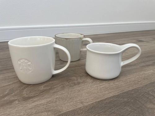 three white coffee mugs sitting on a wooden floor at Permai Japon in Nikko