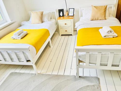 two beds in a bedroom with yellow and white at Horsforth Lodge in Horsforth