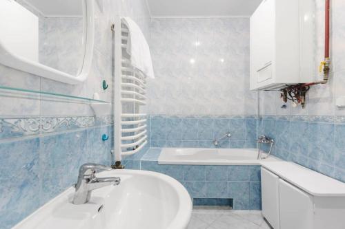 een blauwe en witte badkamer met een wastafel en een bad bij Apartament Astronomiczne miejsce in Przemyśl