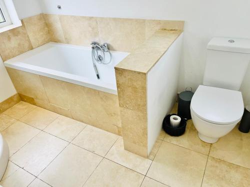 a bathroom with a white tub and a toilet at Horsforth Lodge in Horsforth