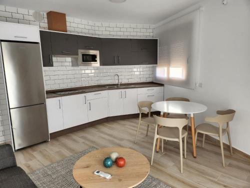 a kitchen with white cabinets and a table and chairs at Apartamentos Doña Emilia in Adeje